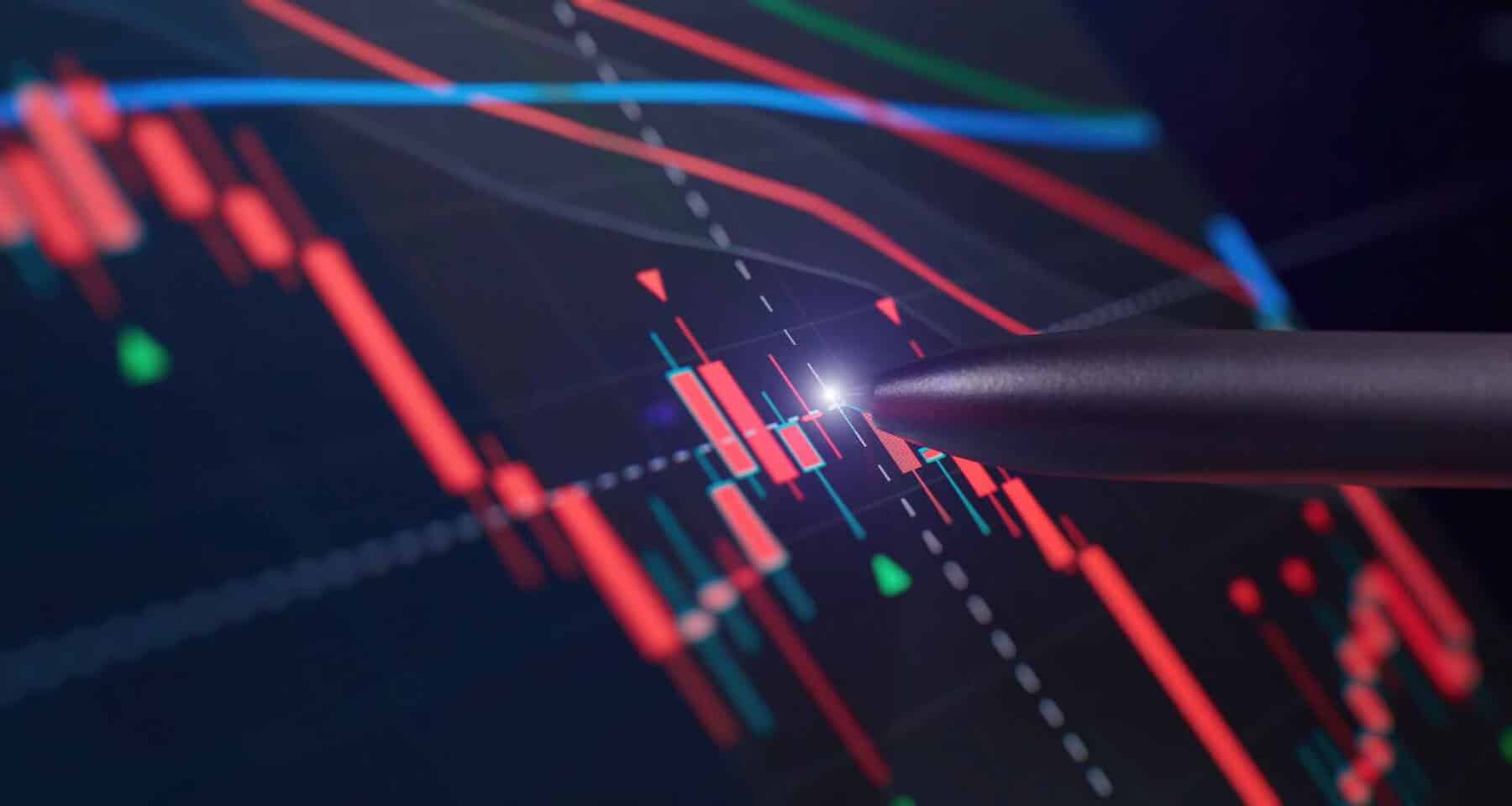 A stylus points at a glowing spot on a digital financial chart displaying red and green candlesticks, trend lines, and data, representing stock market analysis.