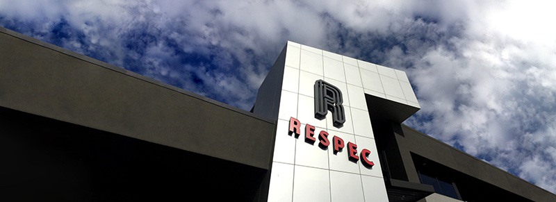 Modern building with a white facade featuring the word RESPEC in bold red letters under a large stylized R, set against a partly cloudy sky.